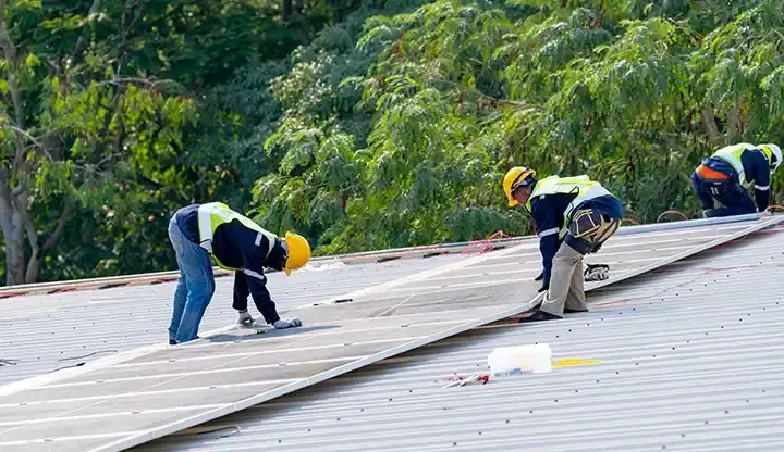 Roofing professionals installing a commercial membrane roof in bright daylight
