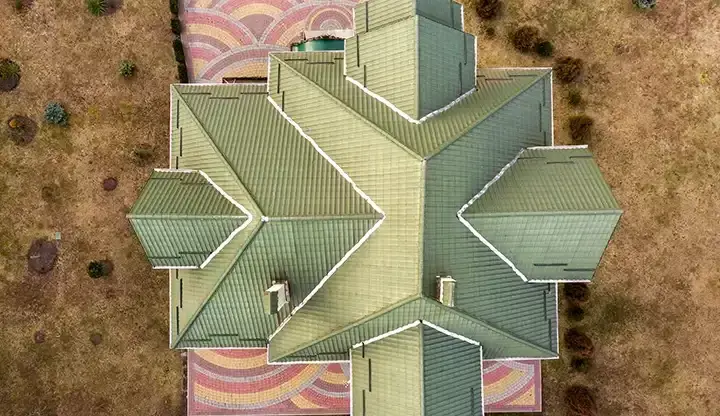 Aerial view of a complex green shingle roof after storm damage assessment